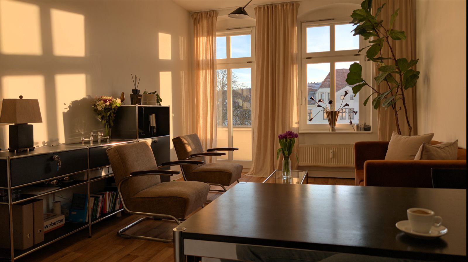 Der Praxisraum im warmen Abendlicht: zwei Sessel, ein Sofa und große Fenster