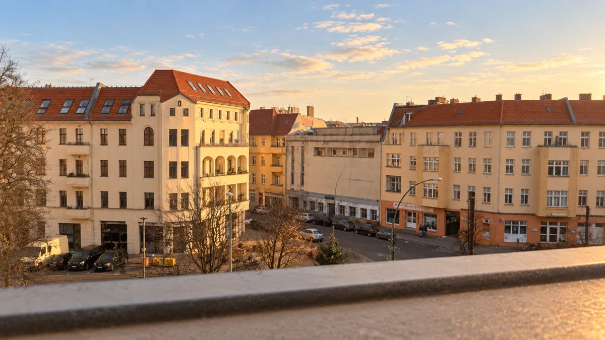 Blick aus der Praxis auf die gegenüberliegenden Altbauten mit roten Dächern im Abendlicht.